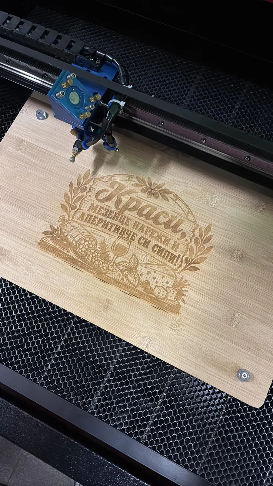 A wooden board with decorative engraved lettering in a laser machine