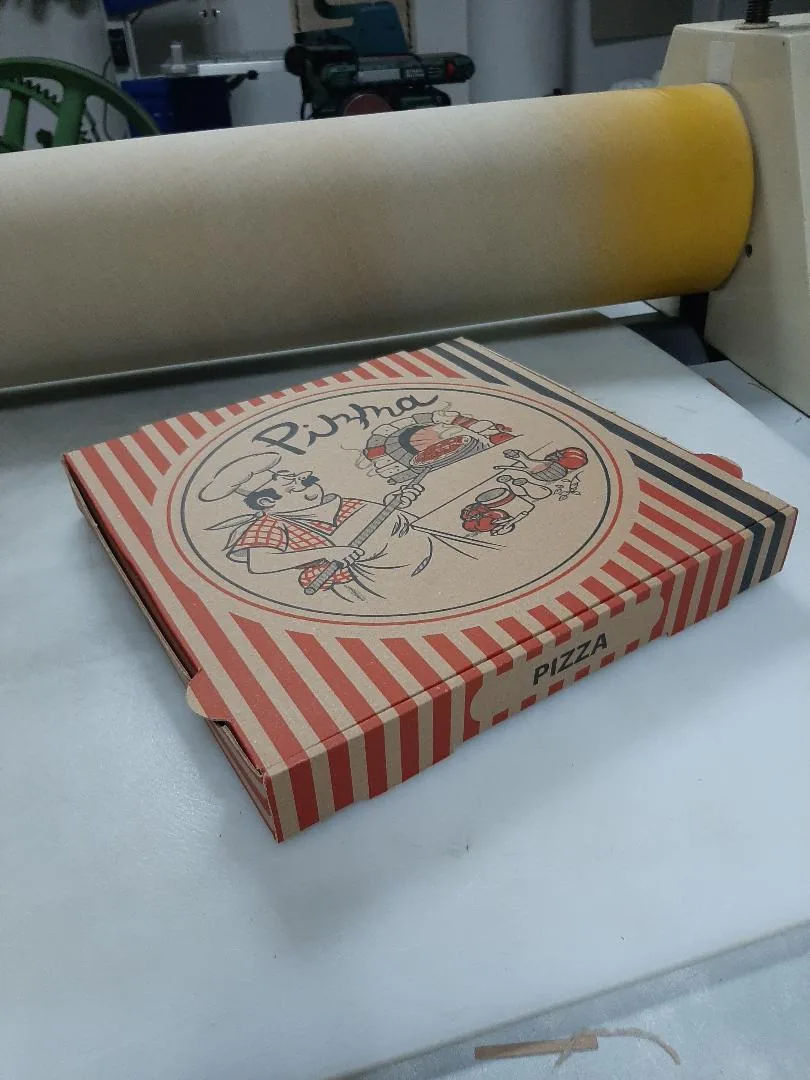 A corrugated pizza box with colour printing on the workbench